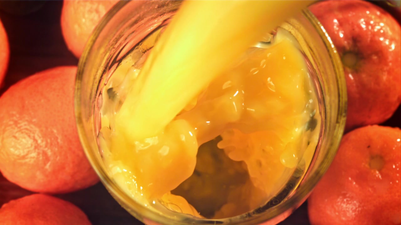 Versamento di succo d'arancia fresco con polpa in un bicchiere.