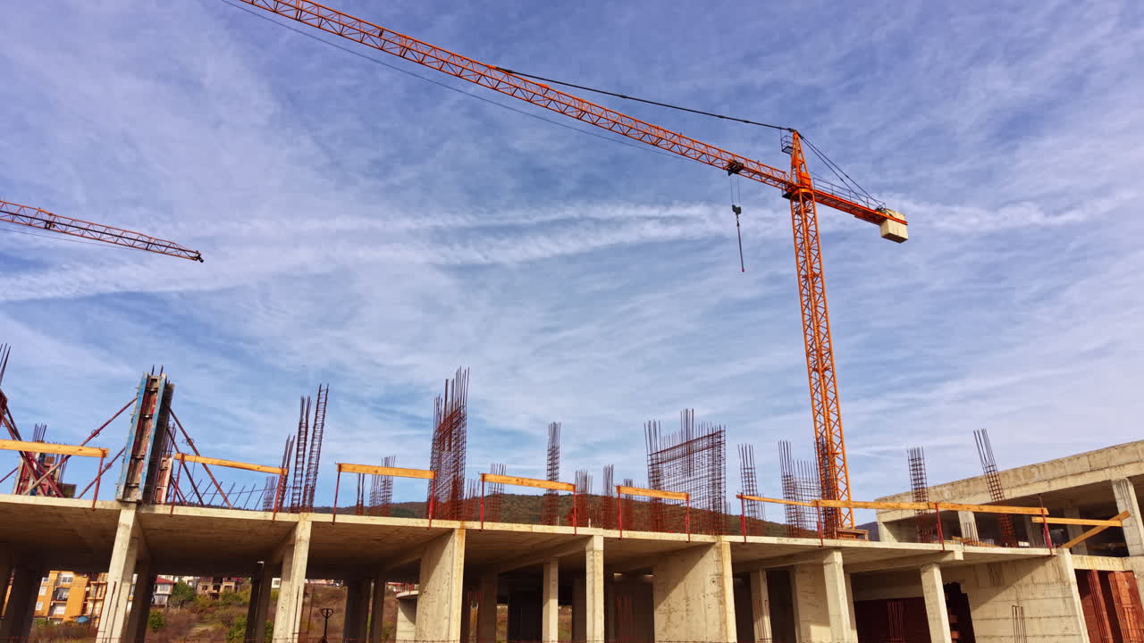 Cranes tower above a bustling construction site under a bright blue sky, showcasing the growth of urban development in a vibrant landscape