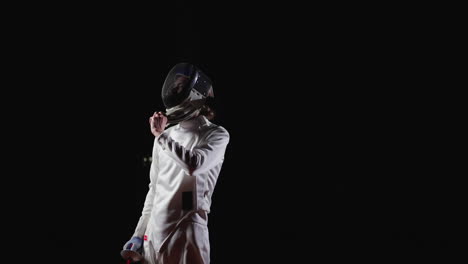 a young man in a fencing uniform, holding a sword, and looking up