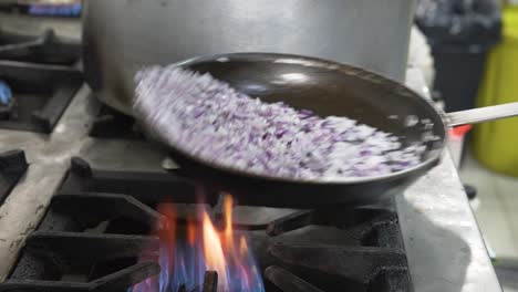 cebollas rojas en llamas fritas en una sartén