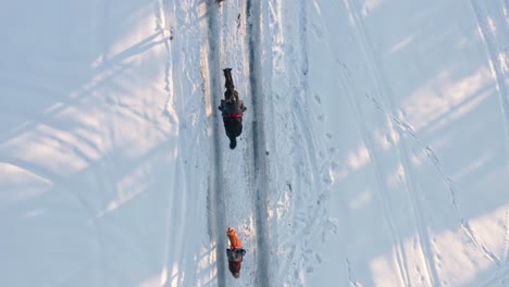 aerial top tracking view of jockeys riding horses in winter snowy landscape