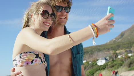 beautiful caucasian couple taking selfies on the beach