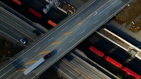 normal speed bird's-eye zoom out drone shot of bridge of the highway 1 and yellowhead highway in kamloops bc canada with trains and vehicles moving one the streets on a sunny, colourful day