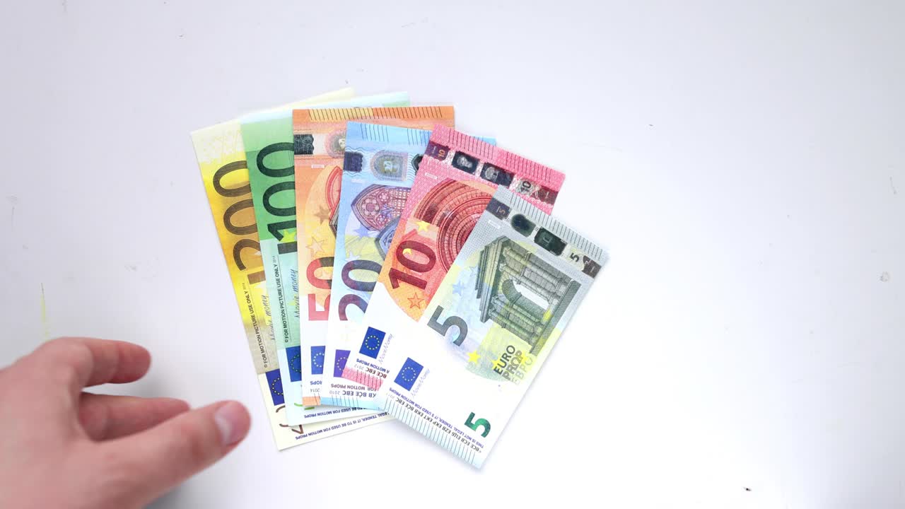 유로 지폐를 고 있는 사람이 명확한 배경 위에 그 지폐를 놓고 있습니다.