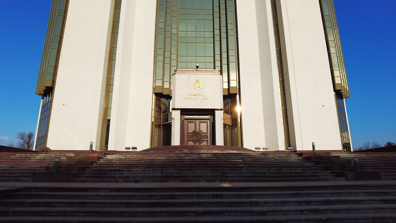 Chisinau, Moldova - December 23, 2021: The bright sunlight shines on the steps leading to a prominent government building. The architecture features striking glass and golden elements that catch the eye