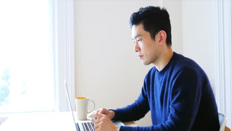 man using laptop while having cup of coffee 4k