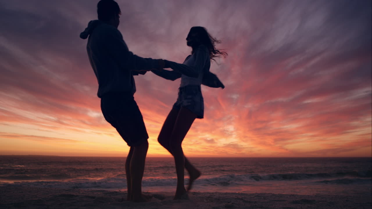 Happy couple dancing on beach enjoying honeymoon in nature at sunset silhouetted wide shot RED DRAGON