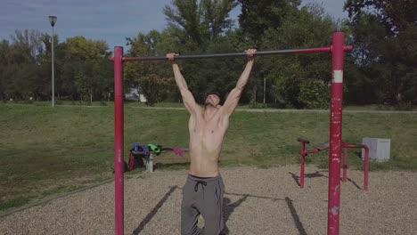 Hermoso-Joven-Musculoso-Caucásico-Haciendo-Pull-Ups-En-La-Naturaleza-Solo-Durante-La-Práctica-Individual