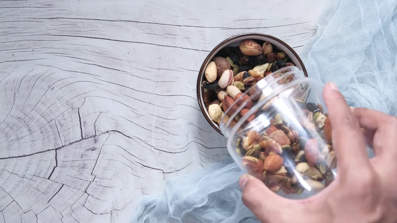 가운 나무 테이블 에 있는 그 에 항아리 에서 혼합 된 견과류 를 는 사람