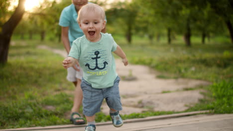 cute brothers walking in park. elder brother hel junior to make steps outdoors