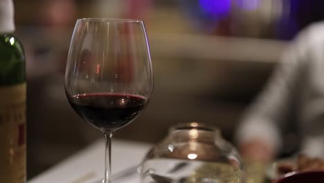 a wine glass filled with red wine on a restaurant table, with blurred background and warm lighting