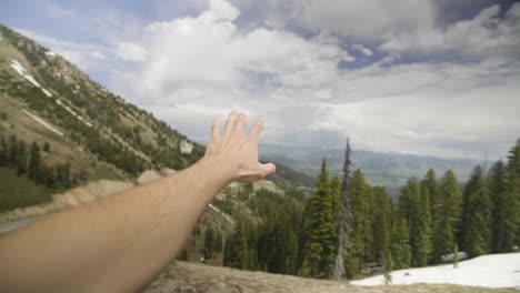 mano extendida para tocar montañas en la distancia