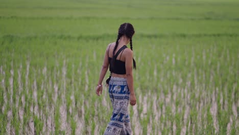 young woman walking through a green rice field