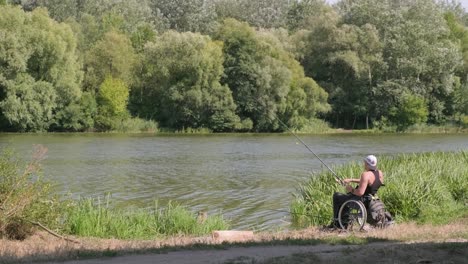 hombre con discapacidad pescando en un lago. silla de ruedas. acampar. verano