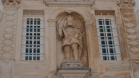 stone statue of a king on a building facade