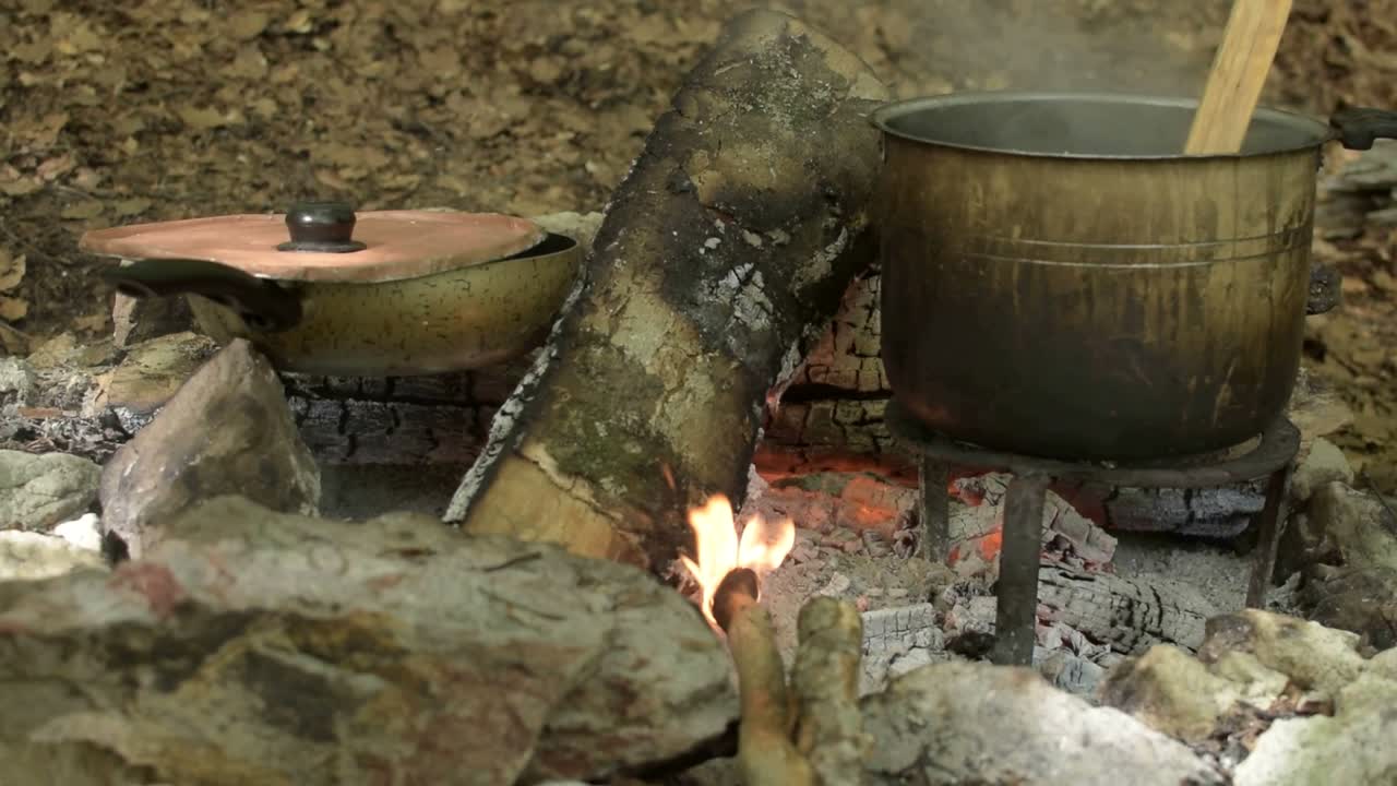 cocinando en la naturaleza en la fogata, durante las vacaciones de verano italianas - ferragosto