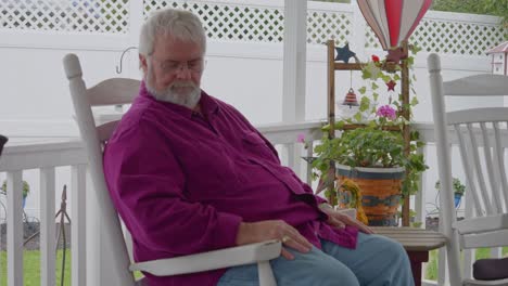 A-Senior-Male-a-Sleep-in-a-Rocking-Chair,-on-a-Deck,-Enjoying-His-Retirement-on-a-Autumn-Day