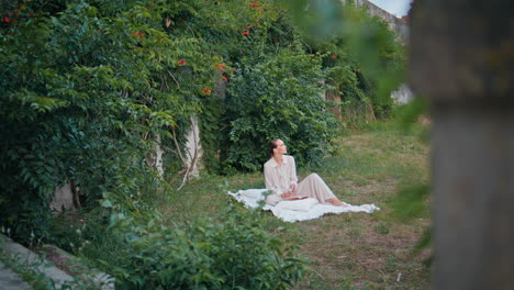 serene girl enjoy picnic at park greenery. attractive calm woman sitting blanket