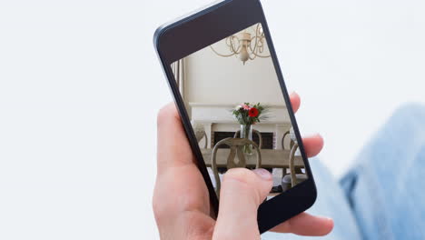 persona que sostiene un teléfono inteligente con interiores modernos de comedor mostrados en la pantalla