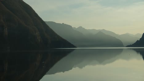 a relaxing and calming scene of a lake surrounded by mountains in northern italy