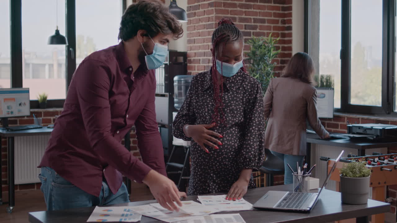 Pregnant employee working with man on business charts