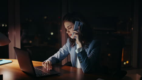 exhausted business woman calling telephone working on laptop evening close up.