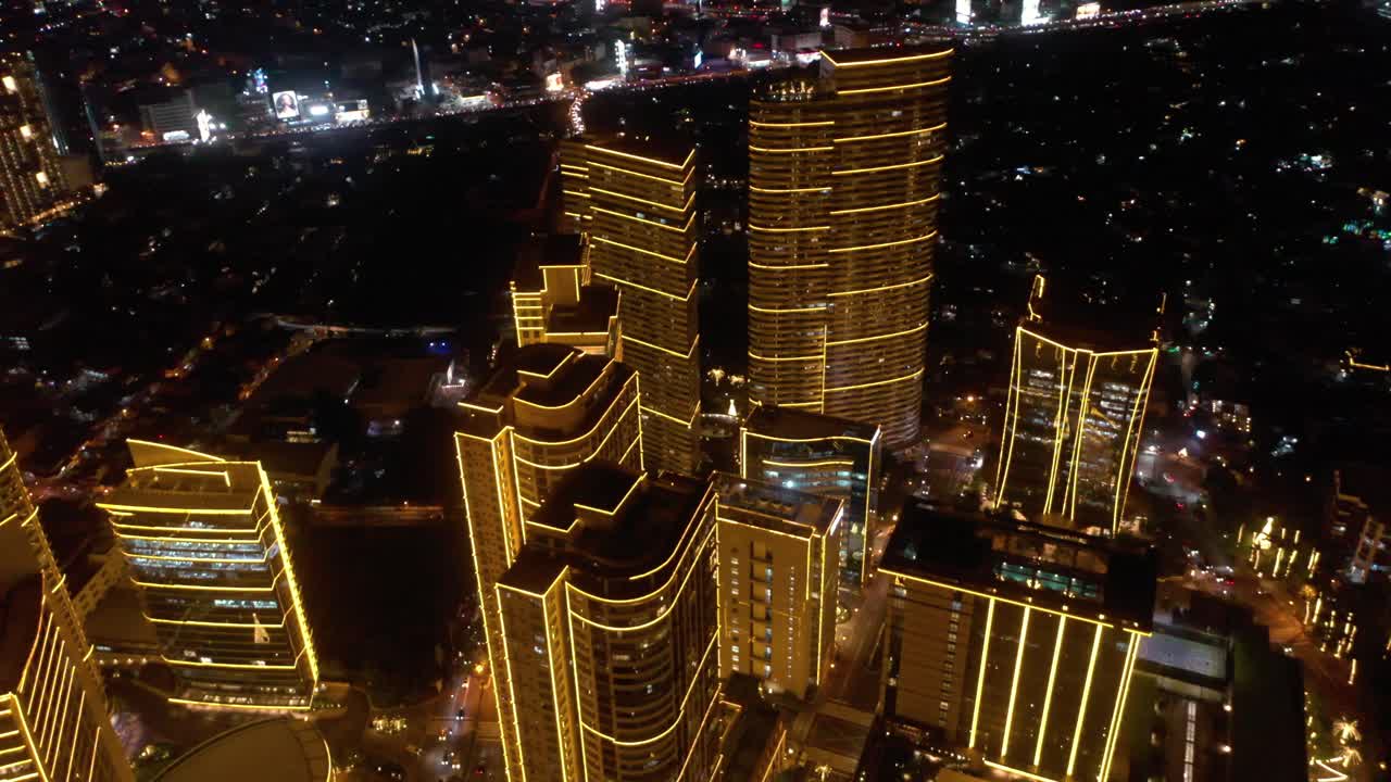 Stunning aerial footage of Rockwell Center skyscrapers in Makati, Metro Manila, glowing with lights at night and surrounded by the vibrant energy of the city skyline.