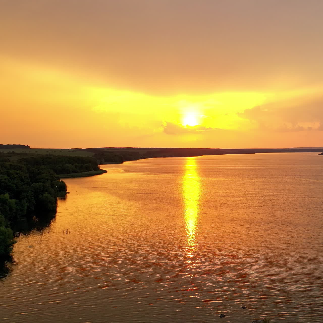 Amazing view of golden path over the river at sunset. Fantastic landscape of nature in the evening. Aerial view. Camera moves forward.