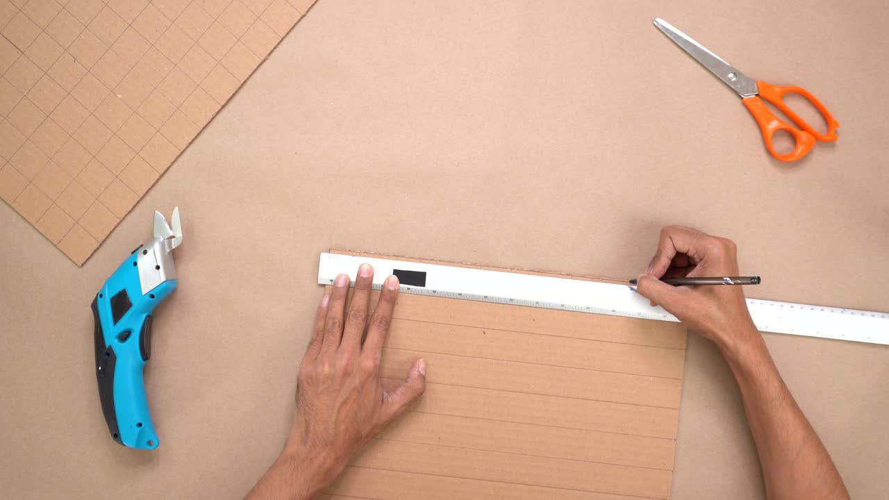 Mani che lavorano il cartone con degli strumenti su una superficie piana