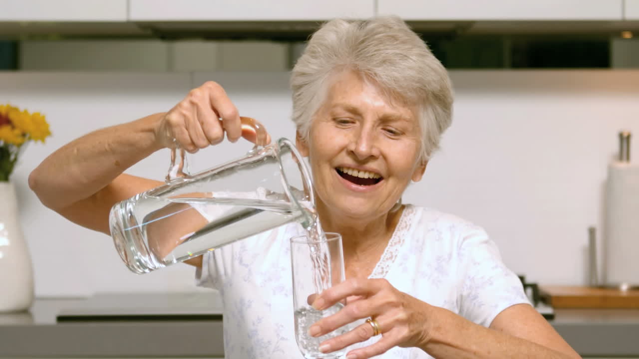 Rentnerin gießt Wasser ins Glas