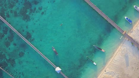 Stunning-aerial-flight-over-clear-turqoise-water-at-the-beach-in-Mabul,-Malaysia