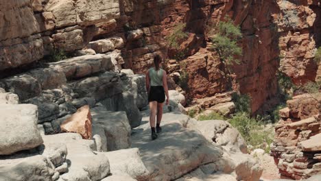 Close-view-of-young-caucasian-woman-walking-up-to-and-edge-of-a-cliff-in-Paradise-Valley,-Agadir,-Morocco