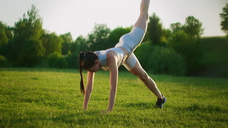 Woman-athlete-involved-in-fitness-in-park-doing-leg-lifts-on-mat.-Workout.-Work-on-a-beautiful-body-in-the-morning-or-at-sunset.-Exercises-for-leg-and-hip-muscles