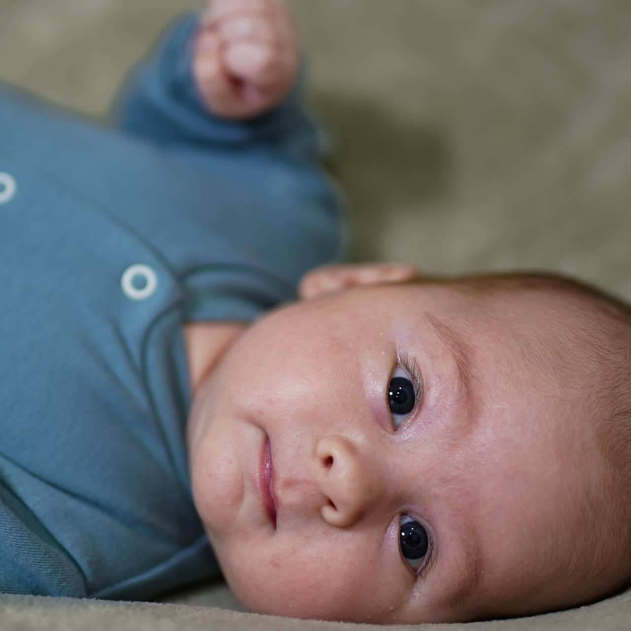 Sweet little baby looking straight into camera. Adorable baby face close up. Grey background