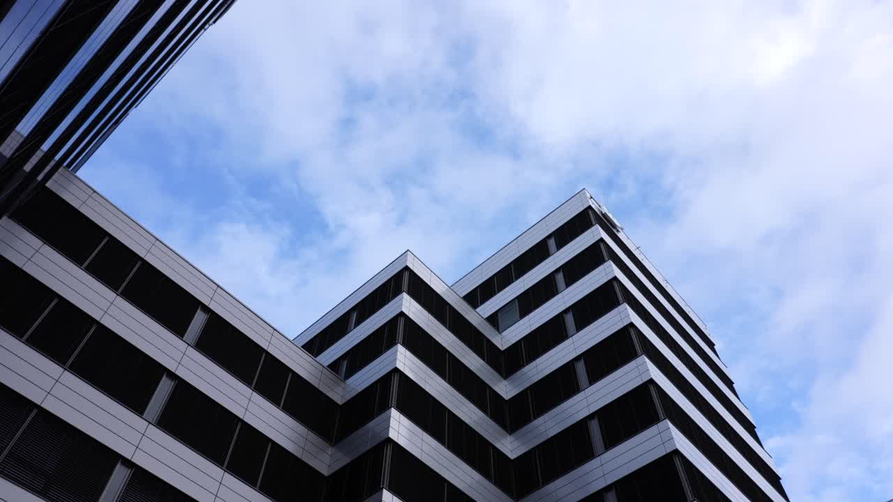 moderno centro de negocios de varios pisos con ventanas oscuras y nubes blancas en el cielo