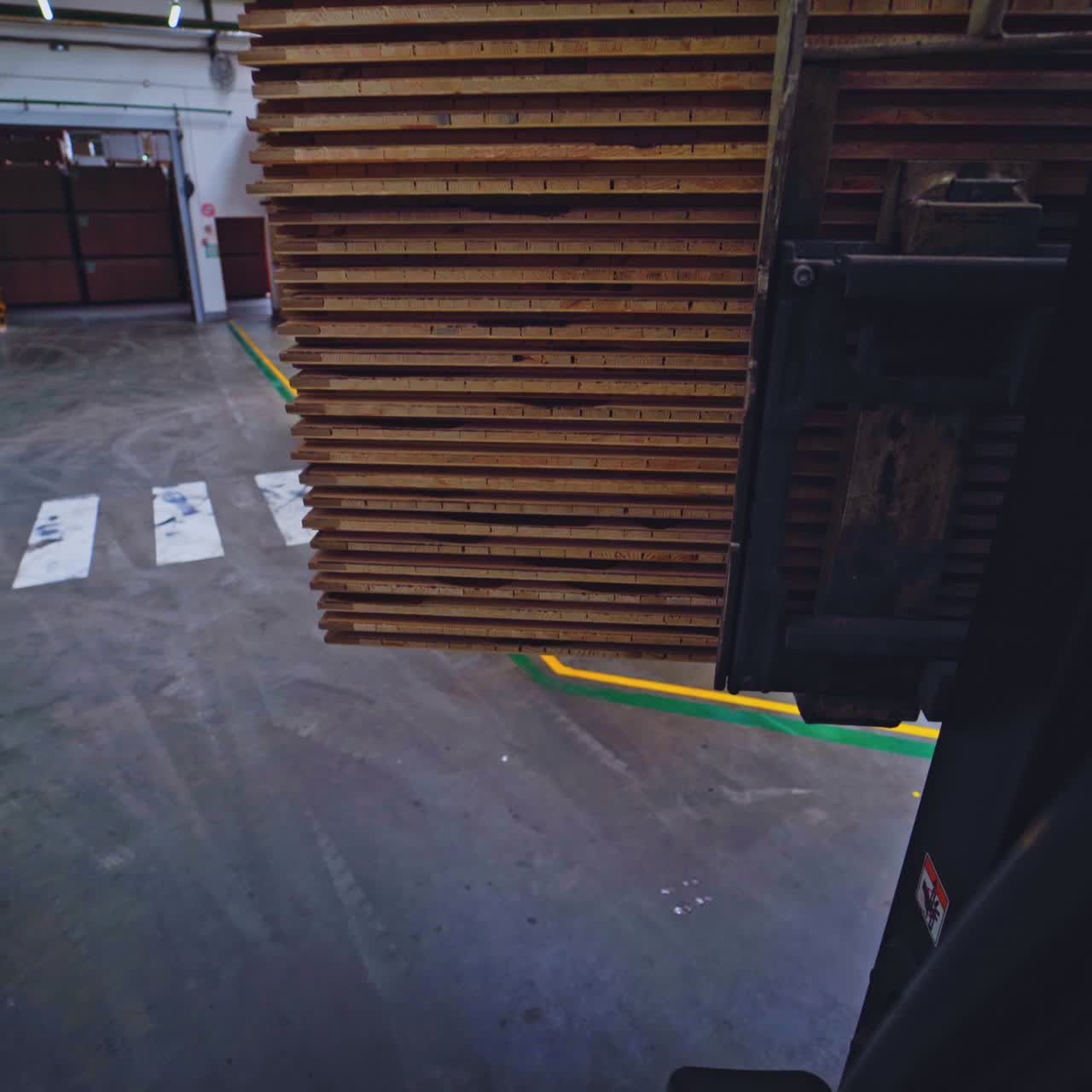 Forklift is carrying wooden panels. Woodworking factory indoors. Huge industrial building for furniture production.