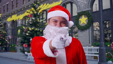 un primer plano de santa claus asiático apuntando a la cámara en la noche de navidad
