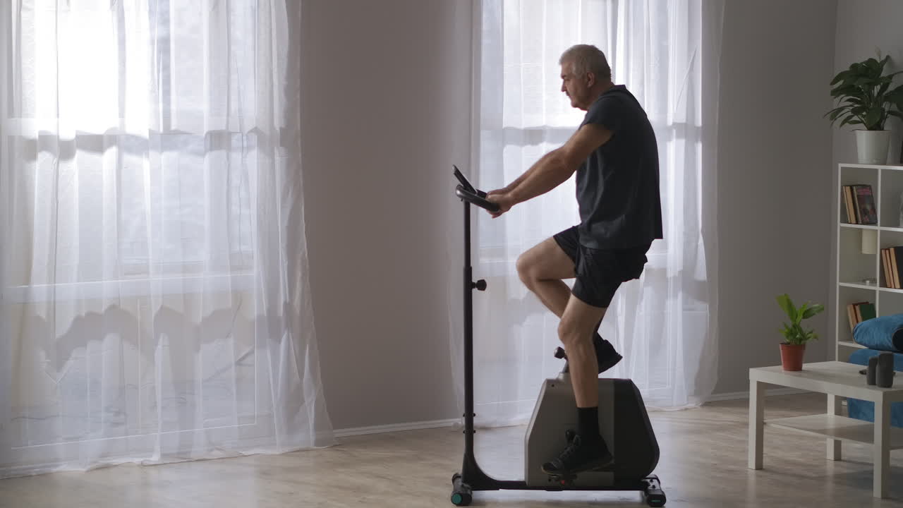 modern stationary bicycle in homeadult man is training on gym equipment losing weight and keeping good physical condition