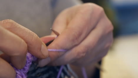 macro vista: mujer teje hilo en la ronda, artesanía hilo y agujas
