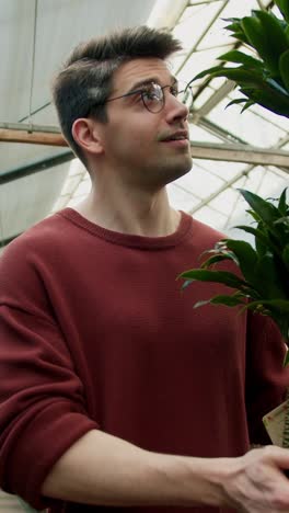 man holding plants in a greenhouse