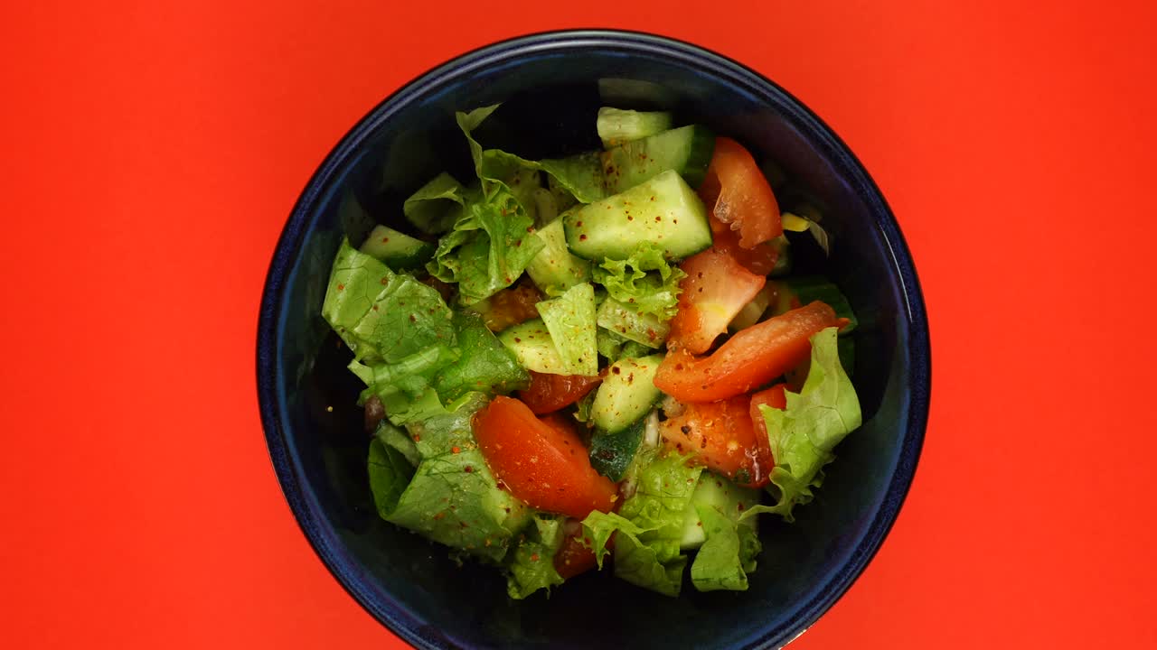 el tazón de ensalada está girando sobre un fondo rojo.