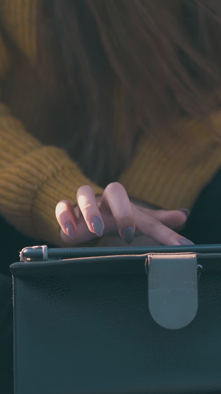 long haired girl uses tablet sitting on red plaid at campsite in autumn evening extreme close view