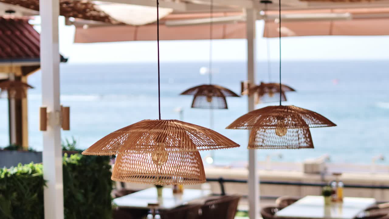 Elegant wicker lamps hanging over terrace tables with Atlantic view in Adeje