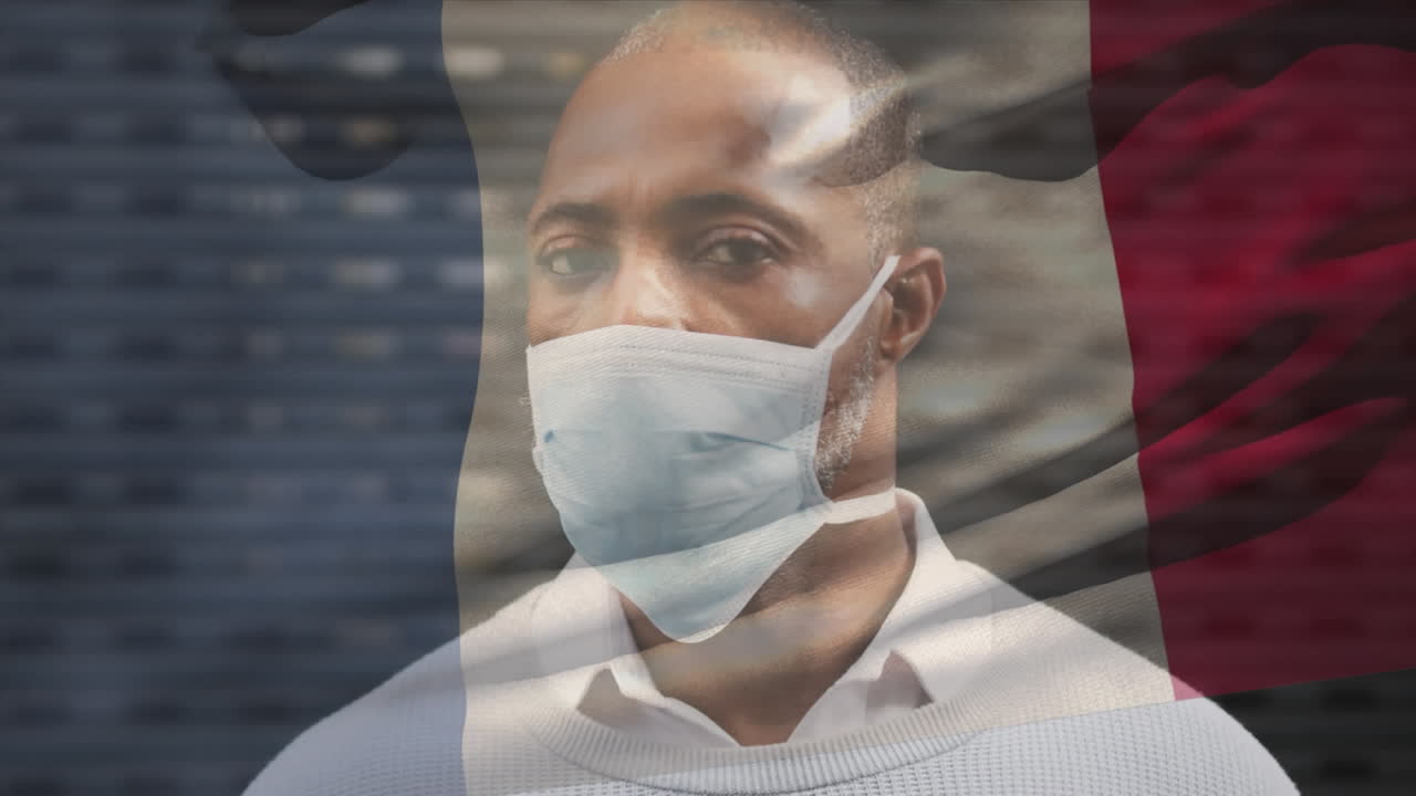 Animation of flag of france waving over man wearing face mask during covid 19 pandemic