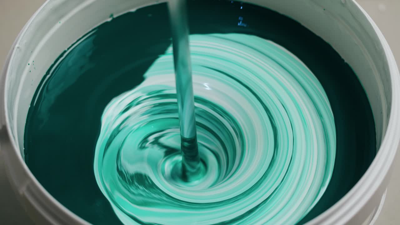 Primo piano di vernice verde e bianca che si mescola in un secchio