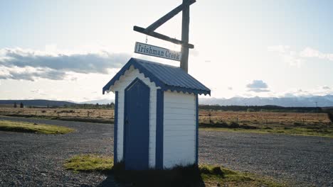 irishman creek station hut backlit by low sun and its sign moving in the fresh mountain breeze