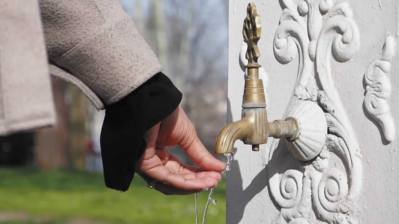 женщина пьет воду из исторического фонтана