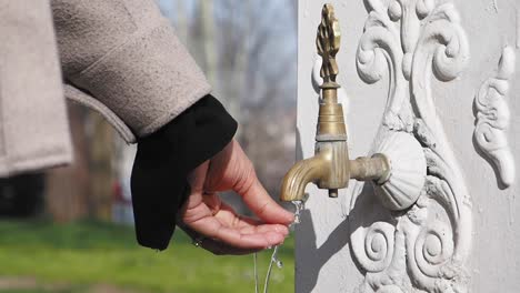 mujer bebiendo agua de una fuente histórica