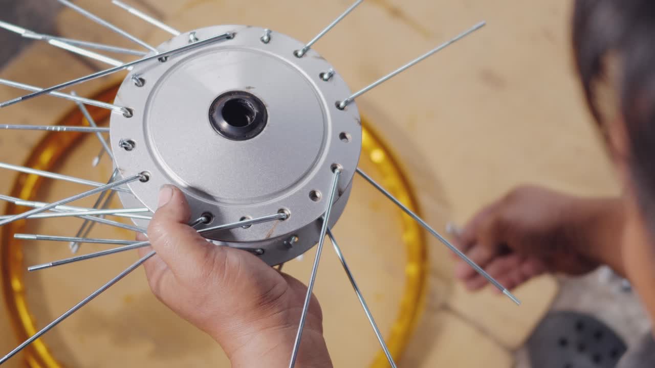 técnico hombre trabajando rueda de motocicleta tiene rayos tejer en mecánico nueva rueda de acero
