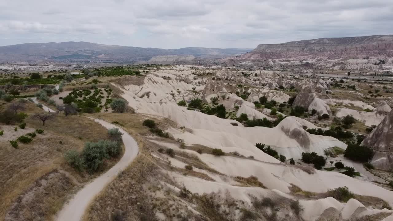 카파도키아의 풍경, 터키의 고레메 근처의 바위 형성과 구름이 가득한 하늘 위에서 앞으로 나아가는 공중 드론